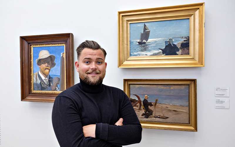 Bilde av en mann som poserer med et maleri