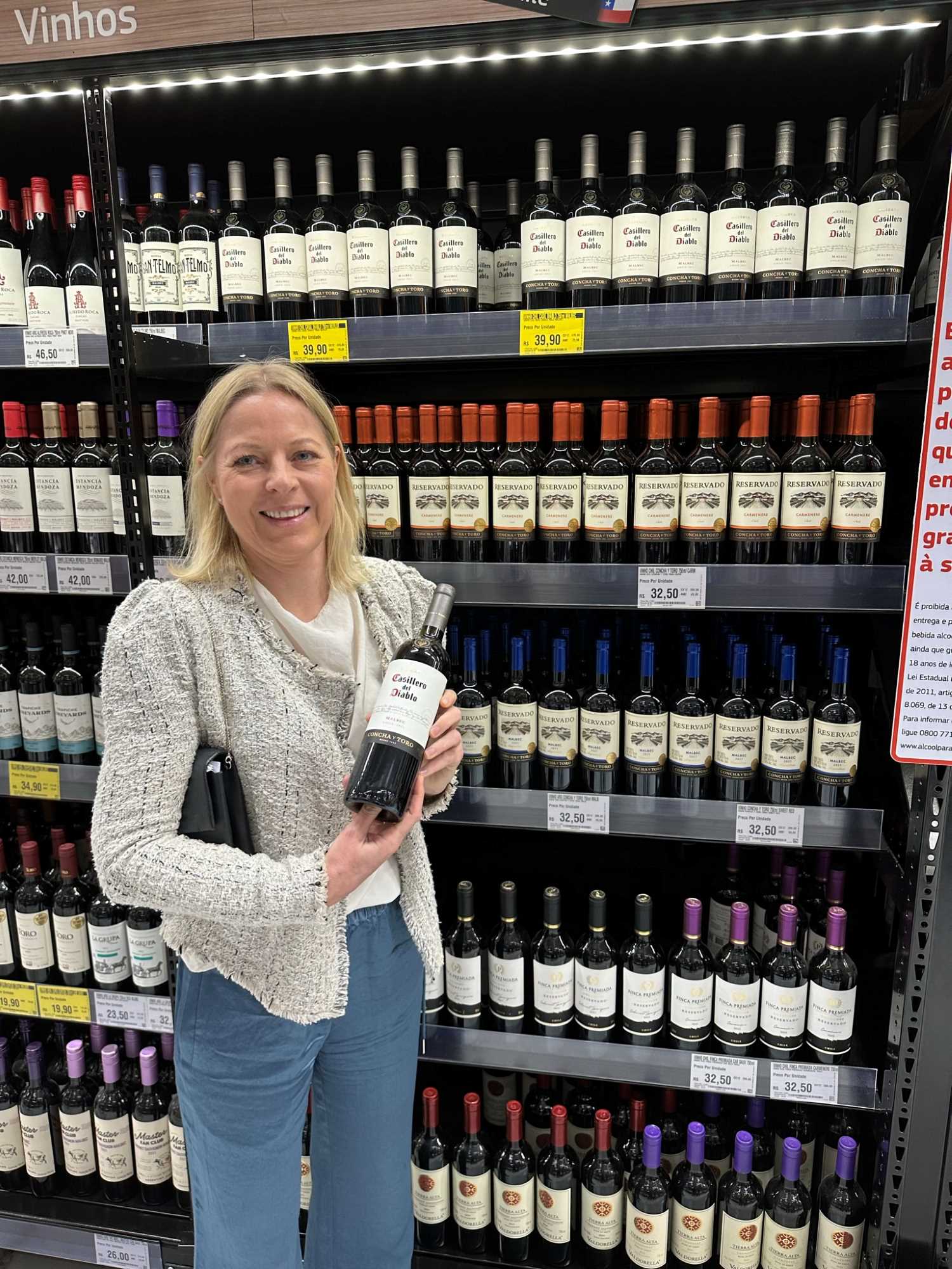 Kvinne med vinflaske i supermarked
