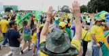 Folkemengde i Brasil bærer nasjonens flagg og løfter hendene i været. 