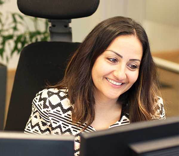 Ung kvinne arbeider med en datamaskin og smiler.