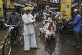 Gatescene fra Mumbai. Til venstre en mann på sykkel og i midten flere menn som ser i kamera.